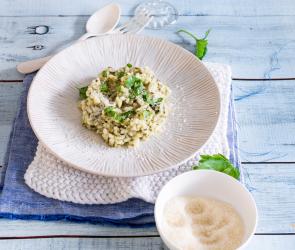 Spinatrisotto auf Teller mit Parmesan in Schälchen