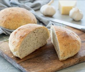 Rustikales Parmesan-Knoblauch-Brot angeschnitten auf einem Holzbrett.