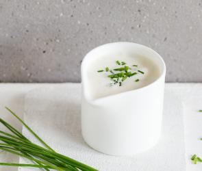 Sour Cream mit Schnittlauch in einem Saucenkännchen.