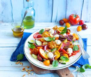 Panzanella mit bunten Tomaten, Mozzarella und Nektarinen auf einem Teller.