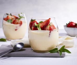 Weiße Creme mit Erdbeeren in zwei Gläsern.