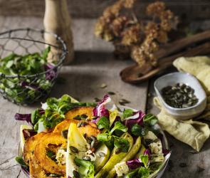 Gebratene Kürbisscheiben auf buntem Herbstsalat.