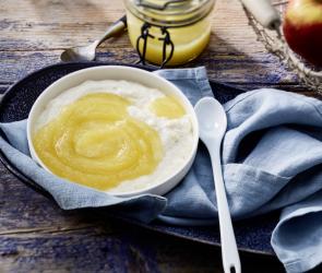 Heller Brei mit Apfelmus im Schälchen mit kleinem Löffel.