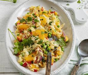 Reissalat mit Currysauce und Mandarinen in einer Servierschale.