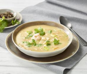 Suppe mit Garnelen und Petersilie in einem tiefen Teller.