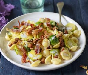 Nudeln mit Rosenkohl und Speck auf einem Teller.