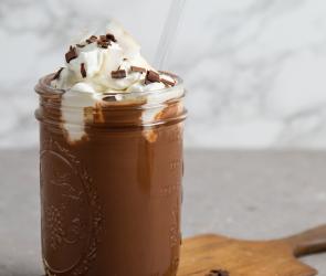 Dunkle Trinkschokolade in einem Glas mit Sahne.