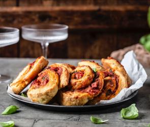 Pizzabrötchen auf Teller mit Glas im Hintergrund.