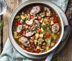 Linseintopf mit Bockwurst in einer Schüssel.