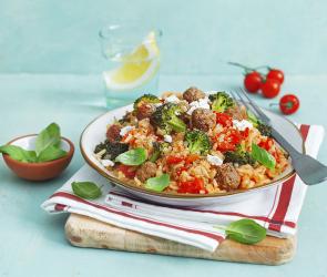 Reistopf mit Hackbällchen auf einem Teller, dekoriert mit einem Stofftuch