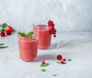 Roter Smoothie in zwei Gläsern mit Beeren garniert.