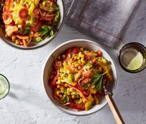 Bunter Mais in Schüssel mit Tellern daneben.