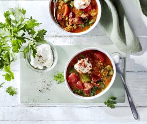 Spanische Linsensuppe mit Frischkäse in einer Schale.