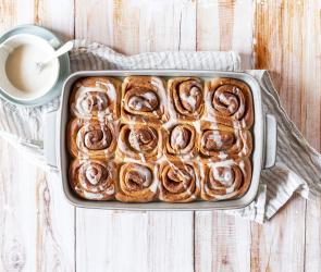 Vegane Zimtschnecken in Auflaufform mit weißem Guss in Schälchen.