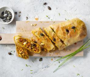 Angeschnittener Kürbisstrudel mit Feta, Speck und Kürbiskernen