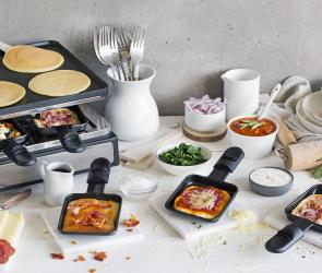 Flammkuchen für Raclette in Pfännchen auf einem gedeckten Tisch.