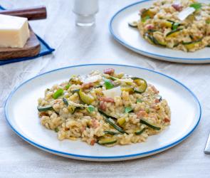 Risotto mit Zucchini und Speck auf einem Teller