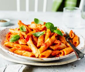 One-Pot-Pasta mit Tomaten-Curry-Sauce in einem weißen Teller serviert.