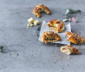 Schinken-Käse-Croissants auf einem Kuchengitter mit Backpapier.