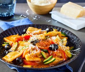 Ravioli mit Gemüse auf einem dunklen Teller.