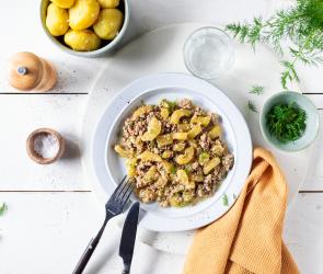 Schmorgurken mit Hackfleisch auf einem weißen Teller, dazu Kartoffeln.