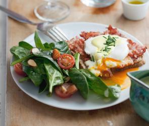 Eggs Benedict mit Salat auf einem Teller.