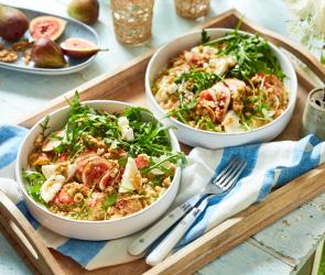 Couscoussalat mit Rucola und Ziegenkäse in zwei Schüsseln.