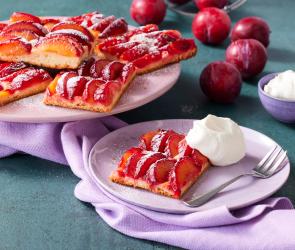 Pflaumenkuchen vom Blech mit Puderzucker in Stücke geschnitten.