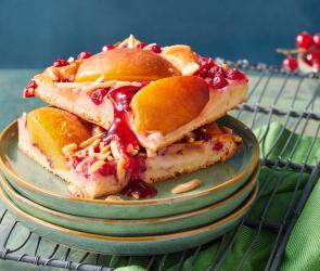 Blechkuchen mit Johannisbeeren und Nektarinen in Stücke geschnitten auf Tellern.