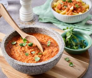 Tomatensauce mit Basilikumblättern und einem Holzlöffel.