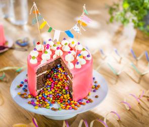 Piñata-Torte angeschnitten mit bunten Schokolinsen in der Mitte.