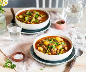 Rindfleischeintopf mit Bohnen in zwei Schüssel auf einem gedeckten Tisch.