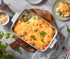 Rosenkohl-Kartoffel-Auflauf in einer hellen Form mit Petersilie getoppt.