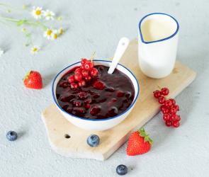 Rote Grütze in Schale angerichtet mit Beeren und Vanillesauce