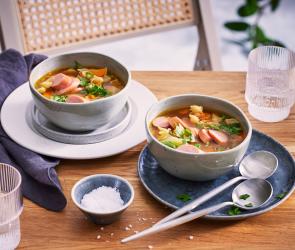 Gemüsesuppe mit Nudeln in Suppenschüsseln auf einem Tisch.
