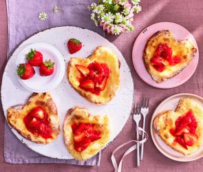 Erdbeer Blätterteig Herzen mit frischen Erdbeeren auf einem Teller.