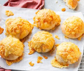 Käsebrötchen mit knuspriger Käsekruste auf einer Platte mit Tuch.