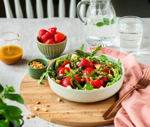 Spargelsalat mit Erdbeeren in einer Schüssel auf einem gedeckten Tisch.