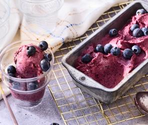 Blaubeer-Joghurt-Nicecream mit frischen Beeren garniert.