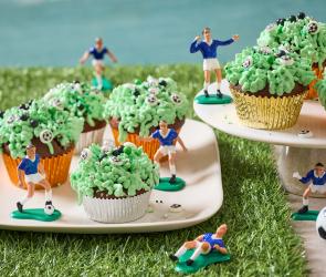 Fußball Muffins mit grünem Frosting und kleinen Fußball Figuren daneben.
