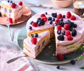 Naked Cake mit Beeren ummantelt mit einer rosa Creme.