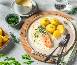 Lachsfilet in Senfsauce mit Kartoffeln auf einem Teller mit Saucière.