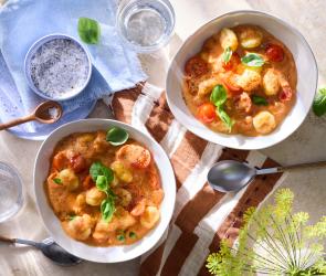 One-Pot-Gnocchi Tomate-Mozzarella in Schüsseln auf einem gedeckten Tisch.