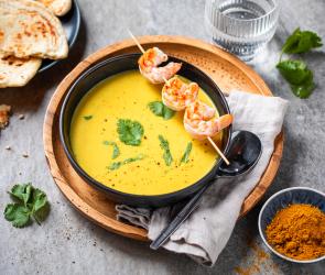 Mango-Curry-Suppe mit Garnelenspieß in einem Suppenteller.