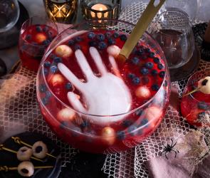Halloween-Bowle mit Hand in roter Flüssigkeit.