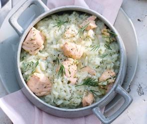 Lachs Risotto in einem hellen Topf mit Fischstücken.