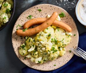 Würstchen mit Kartoffelsalat auf einem Teller.