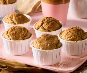 Zuckerfreie Muffins in Papierförmchen auf rosa Tablett.