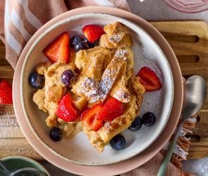 Zwiebackschmarrn mit Puderzucker und frischen Beeren in einem Teller.