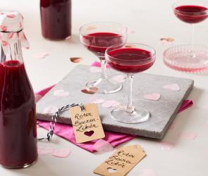 Roter Beerenlikör in Flaschen und eingeschänkt in Likörgläsern.